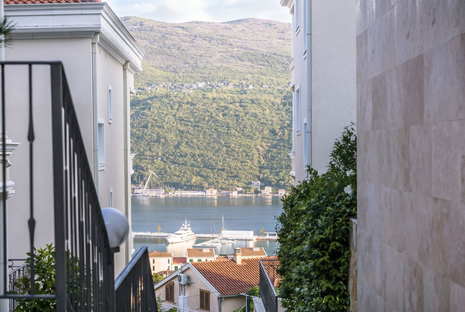 View of the sea and yacht marina from a residential complex in Kumbor, Montenegro, seen from the terrace of a modern building.
