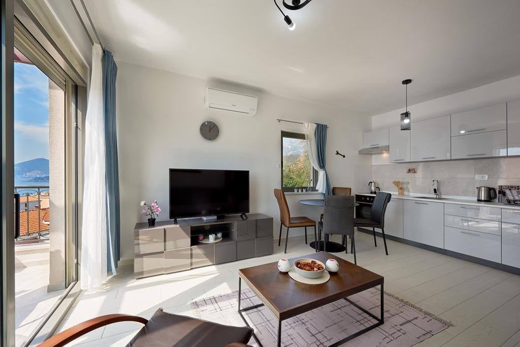 Living room with kitchen in an apartment in Pržno, Montenegro: modern furniture, bright interior, and panoramic sea view.