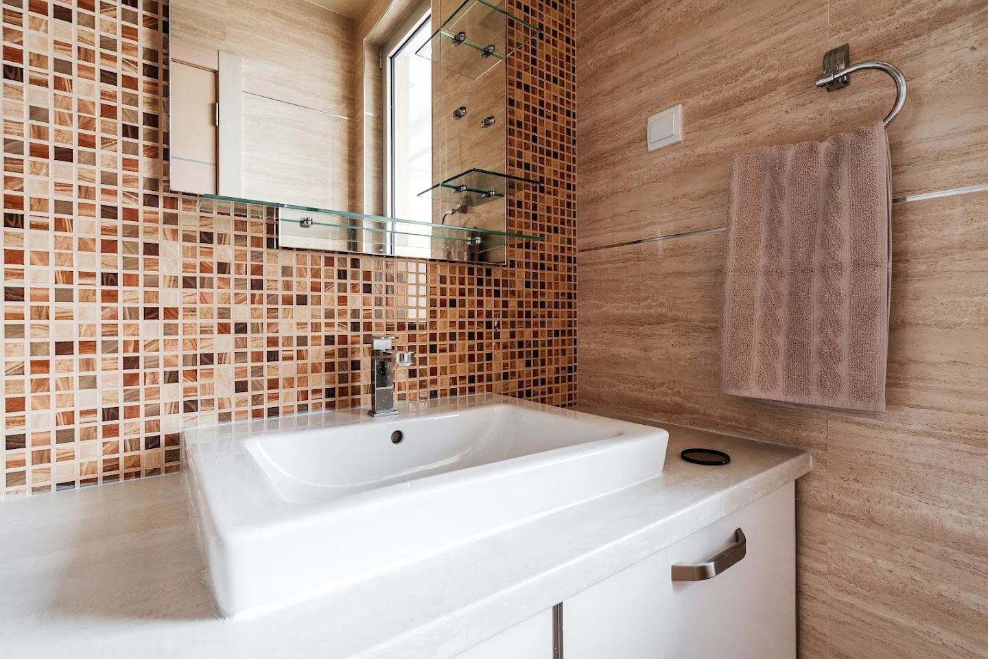 Modern bathroom with mosaic and a white sink in an apartment in Budva, Montenegro.