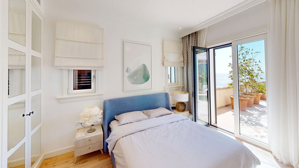 Bright bedroom with a blue bed and access to a terrace with a sea view in a residential complex, Luštica, Montenegro.