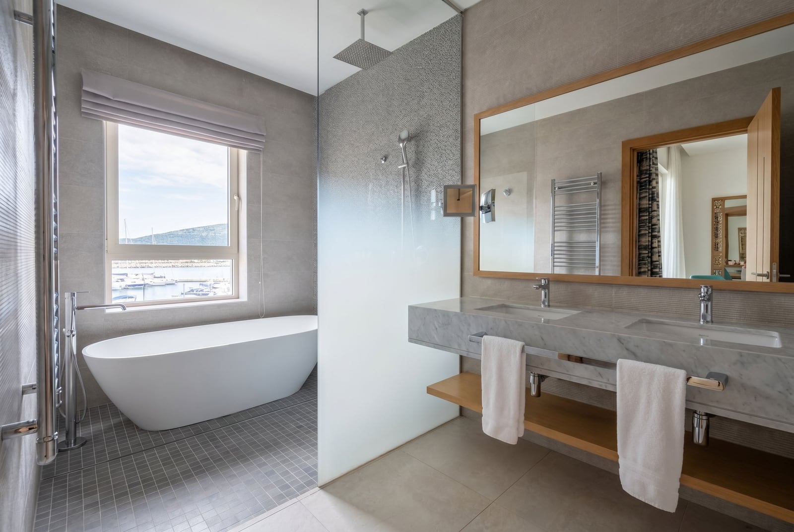 Modern bathroom in Luštica, Montenegro: freestanding bathtub, marina view, marble countertop.