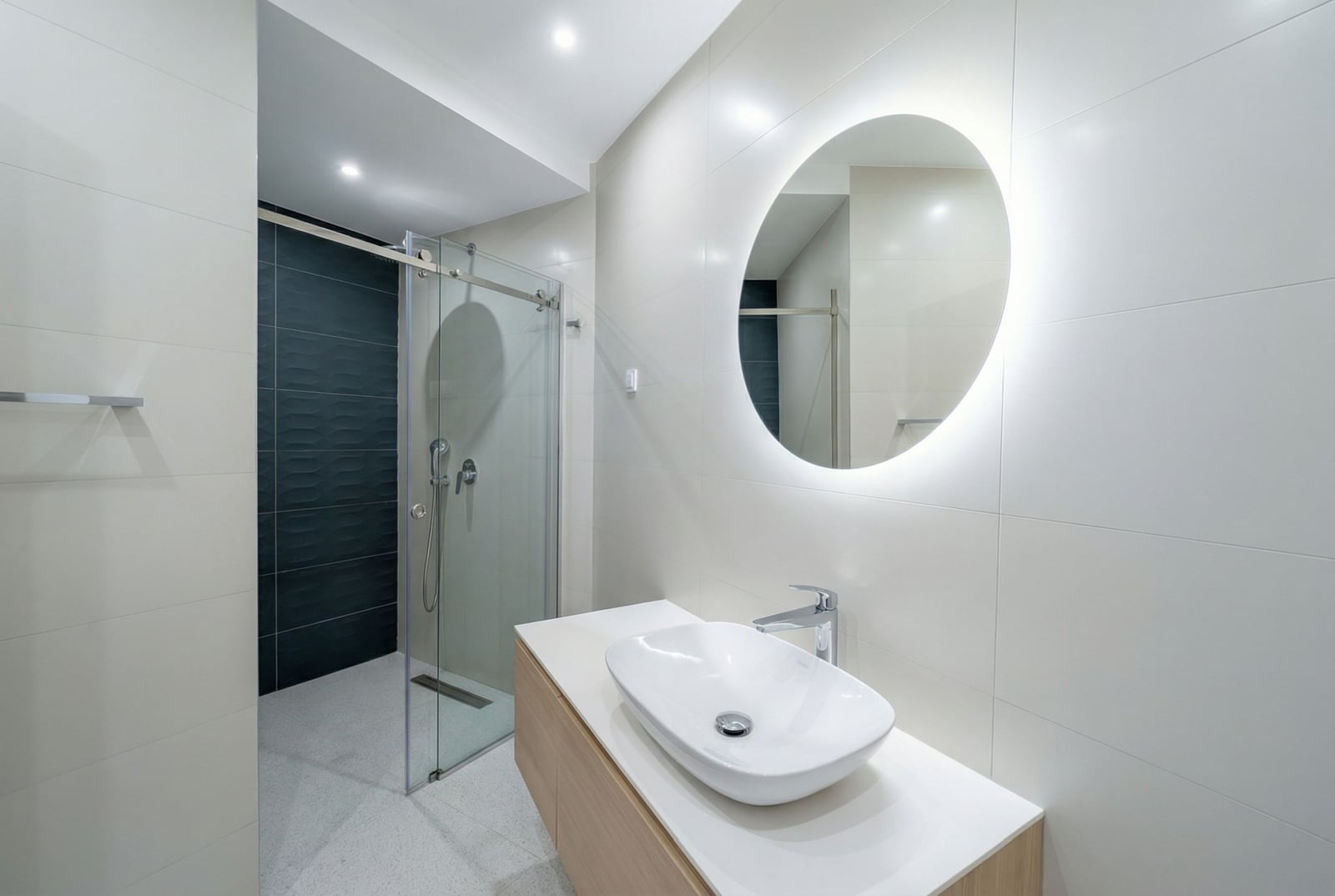 Modern bathroom in an apartment in Bečići, Montenegro: shower cabin, countertop sink, and round mirror.