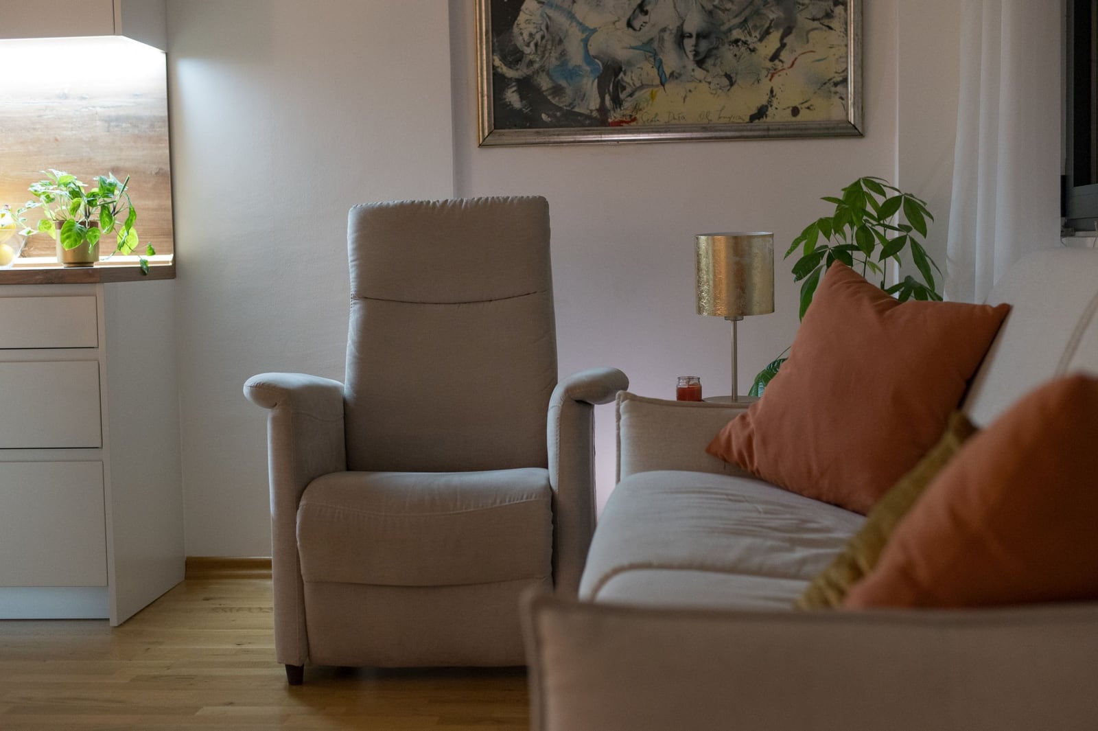 Cozy living room in an apartment in Tivat, Montenegro: light-colored armchair, sofa with cushions, decor, and modern interior.