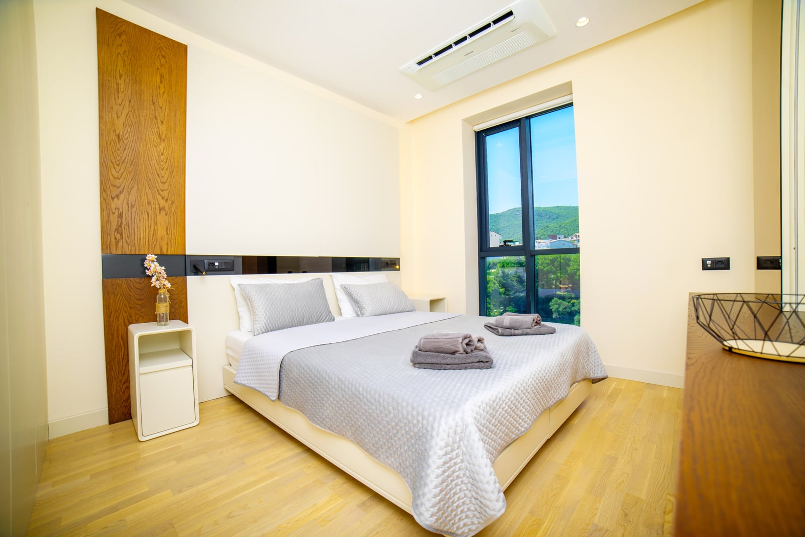 Modern bedroom with a double bed in an apartment in Bečići, Montenegro, with mountain views and air conditioning.